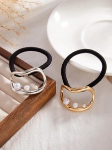 Detail of gold and silver irregular geometric hair ties with pearls on textured fabric
