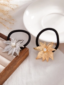 Detail of gold and silver maple leaf hair ties with pearls on an elegant tray