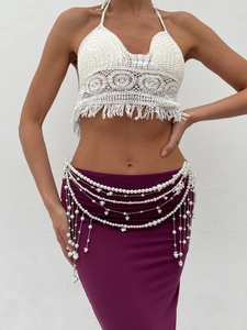 Detail of bohemian pearl waist chain layered over white crochet tassel crop top