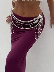 Detail of layered pearl body chain with floral pendant on purple skirt