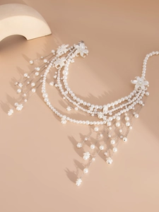 Detailed view of layered faux pearl body chain with floral accents and cascading tassels