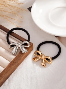 Detail of luxury gold and silver bow hair ties on a rustic wooden stand decor