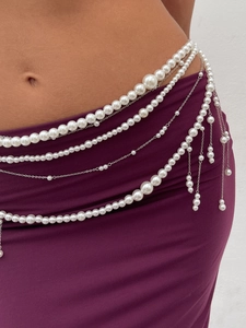 Detail of multi-layer pearl body chain with metallic fringe and tassel accents on waist