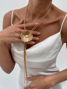 Détail du collier fleur dorée tressée avec perle et pompon métallique sur un mannequin