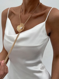 Détail du collier fleur dorée avec perle centrale et chaîne serpent à pompons