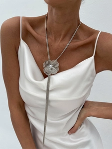 Vue détaillée du pendentif fleur argentée avec perle et longs pompons métalliques fins