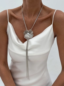 Détail du pendentif fleur argenté avec perle et longue chaîne à pompons sur mannequin