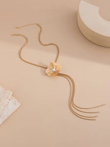Détail d'un collier fleur dorée avec perle blanche et franges métalliques multicouches