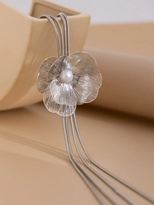 Détail du collier à pendentif fleur argentée avec perle élégante et franges métalliques