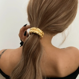 Gouden haarcuff met gesmolten metaallook en onregelmatige textuur op blond haar