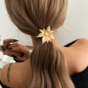 Elegant gold leaf ponytail holder with white pearl detail on textured metal hair tie