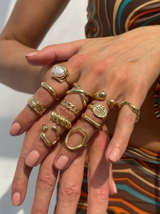 Dettaglio ravvicinato di un set di anelli dorati con perle e design metallici irregolari