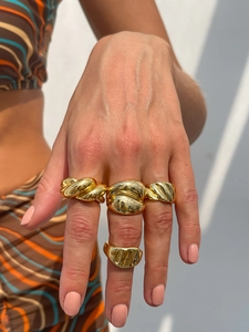Primo piano di anelli d'oro massicci con design ritorti e testurizzati su una modella