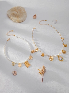 Détail de colliers en perles bohèmes avec pendentifs dorés de coquillages et fleurs