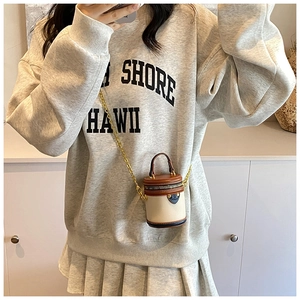 Detailed close-up of mini bucket bag showing grain texture and chain strap on a model