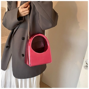 Détail du sac à main rose métallisé avec bandoulière chaîne dorée porté par un mannequin