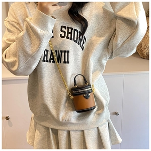 Close-up of mini cylinder bucket bag with contrast stitching and golden chain strap detail