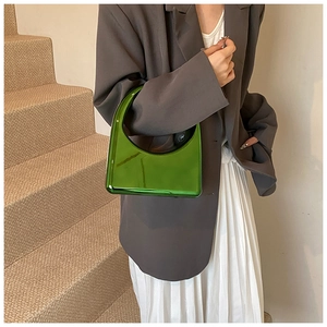 Sac à main vert émeraude brillant avec poignée géométrique ajourée sur costume gris