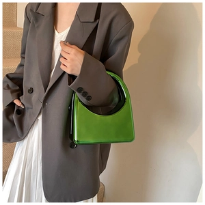 Détail du sac à main vert néon miroir porté avec un blazer et une jupe plissée blanche