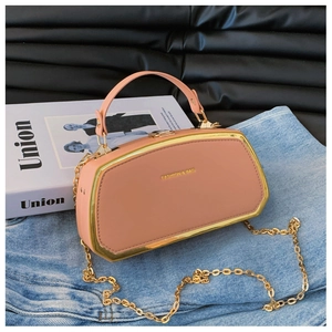 Dettaglio borsa esagonale rosa con cornice dorata e tracolla a catena su denim