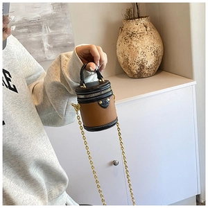 Macro detail of mini cylinder bucket bag in contrast leather with gold chain strap