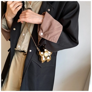 Detailed view of a gold flower-shaped mini bag with a polished mirror finish and chain