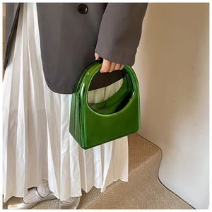 Détail d'un sac à main en acrylique vert néon porté par un mannequin en costume gris