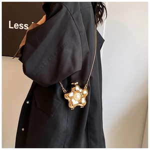 Detailed view of flower-shaped golden evening bag with pearl center and bead chain strap