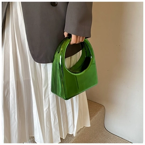 Détail d'un sac à main en acrylique vert métallisé avec poignée ronde lors d'un shooting