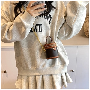 Mini bucket bag with contrast leather detail and golden chain strap shown on person