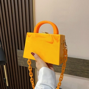 Orange acrylic trapezoid handbag with marble texture, chunky chain, and gold metal clasp
