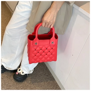 Detail der roten perforierten EVA-Tasche mit Rautenmuster, getragen von einem Modell