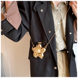 Detail of golden flower-shaped crossbody bag with central pearl and sleek metal chain