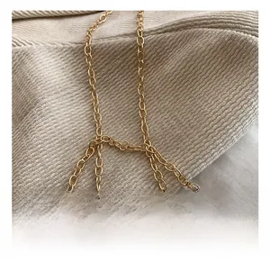 Detailed close-up of the elegant gold metal chain strap on soft beige fabric