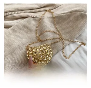 Detail shot of heart-shaped evening bag with champagne gold crystals and fine chain strap