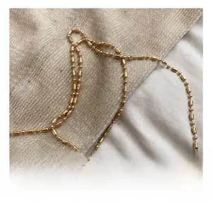 Dettaglio della tracolla a catena dorata con maglie metalliche sferiche e cilindriche lucide