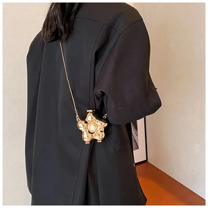 Detailed view of flower-shaped golden evening bag with pearl center and chain