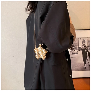 Detailed view of flower-shaped golden metal mini bag with pearl center and chain