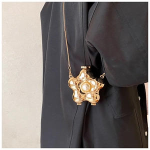 Detailed close-up of golden petal-shaped evening clutch with central pearl inlay and chain
