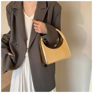 Gros plan d'un sac à main géométrique doré porté par un mannequin en blazer gris chic