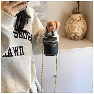 Detailed macro of black pebbled leather mini bucket bag with gold heart clasp and chain