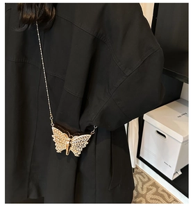Gros plan détaillé d'un mini sac papillon à chaîne avec strass sur tissu noir élégant