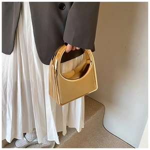 Gros plan d'un sac à main géométrique doré à effet miroir porté par un mannequin élégant