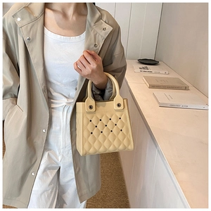 Detail der beige EVA Tasche mit Rautensteppmuster und hohlen Ausschnitten am Tragegriff