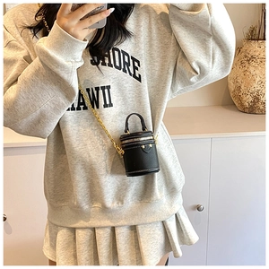 Close-up of mini bucket bag in black lychee leather with golden chain on a model