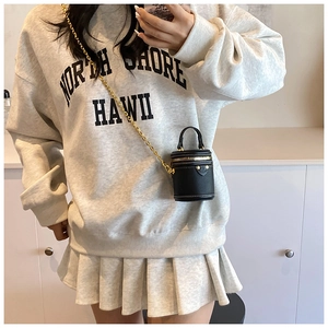 Chic mini cylinder bucket bag in black leather with gold chain strap shown on model