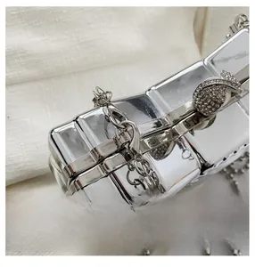 Detail of silver evening clutch featuring a rhinestone bow clasp and metal bead chain