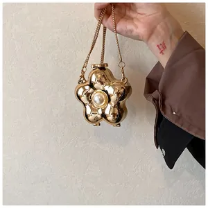 Close-up of golden flower-shaped evening clutch bag with a pearl center and metal chain