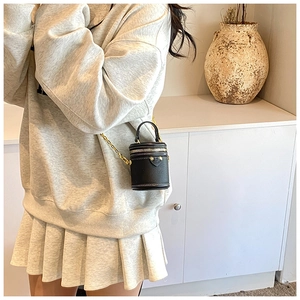 Mini black pebbled leather cylinder crossbody bag with gold chain and top handle