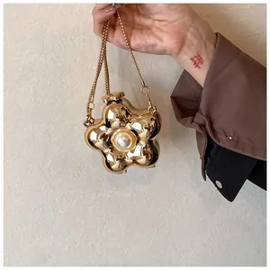 Macro view of flower-shaped golden acrylic evening bag with pearl detail and chain
